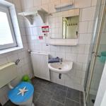 Badezimmer mit Toilette, Waschbecken und Dusche. Blauer Sitz mit Seestern.