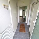 Flur mit grauen und braunen Fliesen, weißen Türen und Heizkörper an der Wand.