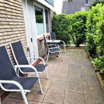 Terrasse mit zwei Liegestühlen und Tisch, umgeben von grünen Hecken.