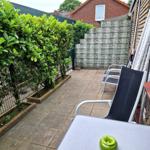 Terrasse mit Sitzgelegenheiten, Beeren und Pflanzen. Hinterhof mit Zaun und Nachbarhaus.