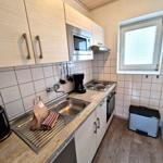 Küche mit Arbeitsplatte, Spüle, Herd, Mikrowelle und Fenster.