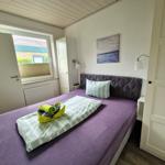 Schlafzimmer mit Bett, Fenster, Wandbild und TV.