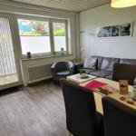 Wohnzimmer mit Sofa, Sessel, Esstisch und Fenster zur Außenseite.