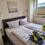 Zimmer mit Doppelbett, Wandbild und Fenster mit Rollos.