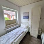 Ein Schlafzimmer mit weißem Bett, Fenster und Kleiderschrank.