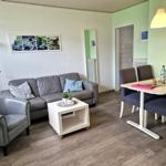 Wohn- und Essbereich mit Sofa, Sessel, Tisch und Stühlen.