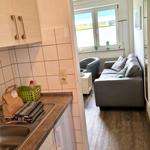 Küche mit Spüle und Arbeitsfläche. Wohnzimmer mit Sofa und Fenster.