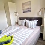 Schlafzimmer mit Bett, Kissen und Wandbild. Zwei Stehlampen und Schrank sind sichtbar.