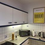 Küche mit weißen Schränken, Mosaikfliesen und Küchengeräten.