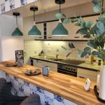 Küche mit Holzbar, grünen Hängelampen und blau-weißen Fliesen an der Wand.