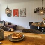 Esszimmer mit runden Tisch, Stühlen und Wandregal mit Weinflaschen.