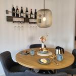 Rundes Esszimmer mit Tisch, Stühlen und Weinregal an der Wand.