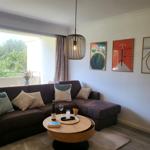 Ein Wohnzimmer mit braunem Sofa, runden Tisch und Wandbildern.