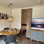 Essbereich mit runden Tisch, vier Stühlen und Fernseher an der Wand.