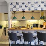 Küche mit Holzbar, drei Stühlen und Delftziegeln an Wand und Bar.