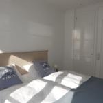 Schlafzimmer mit Bett, Kissen und Tür mit Glasfenstern.