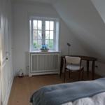Schlafzimmer mit Dachschräge, Fenster, Schreibtisch und Bett