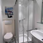 Badezimmer mit Duschkabine, Waschbecken und Toilette. Wandbild und Spiegel sind sichtbar.