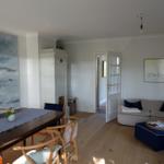 Esszimmer mit Tisch und Stühlen. Wohnbereich mit Sofa und Kissen.