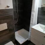 Badezimmer mit Dusche, Waschbecken und WC.