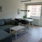 Wohn- und Essbereich mit Sofa, Tisch und Stühlen. Fenster und Balkontür.