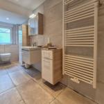 Badezimmer mit Toilette, Waschbecken und Heizkörper an der Wand.