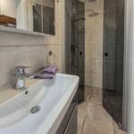 Badezimmer mit Dusche, Waschbecken und Spiegel.