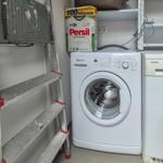 Waschmaschine und Spülmaschine in einem Raum mit Leiter und Waschmittel.