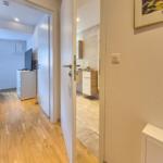 Flur mit Blick in Schlafzimmer und Bad. Holzfußboden und moderne Einrichtung.