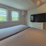 Zwei Betten, Fenster mit Jalousien, TV auf Schrank