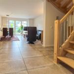 Haus mit Küche, Essbereich und Wohnzimmer. Holztreppe führt nach oben.