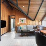 Wohnraum mit Holzwand, Sofa, Tisch und TV. Dachbodenstruktur mit Holzdecke.