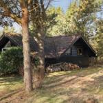 Holzhaus mit Schopfdecke und Holzstapel im Garten