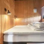 Schlafzimmer mit Bett, Holzwand und Wandlampen. Fenster mit Rollladen.