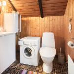 Badezimmer mit Waschmaschine, Toilette und Waschbecken.