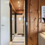 Holzgetäfelte Türöffnung zeigt Flur mit Teppich und Schlafzimmer mit Stehlampe.