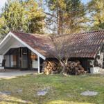 Haus mit Terrasse, Tisch, Stühlen und Holzstapel unter Dach
