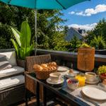 Terrasse mit Tisch, Stühlen, Sonnenschutz und Frühstück.