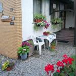 Vor dem Haus steht ein Tisch mit zwei Stühlen. Blumen und Pflanzen schmücken die Terrasse.