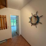 Eingangsbereich mit Holzdekor und runden Spiegel mit Ruderhausmotiv an der Wand.