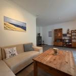 Wohnzimmer mit Sofa, Holztisch und Küchenzeile im Hintergrund.