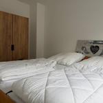 Schlafzimmer mit Bett, weißer Bettwäsche und Holzschrank.