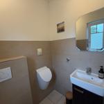 Badezimmer mit Toilette, Waschbecken und Spiegel