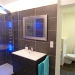 Bad mit Dusche, Waschbecken und Toilette. Dusche mit LED-Beleuchtung.