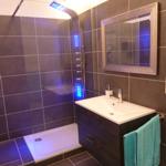 Dusche mit LED-Beleuchtung, Waschbecken und Spiegel an der Wand.