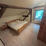 Schlafzimmer mit Holzbett, Fenster und Holzrahmen.