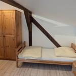 Schlafzimmer mit Holzbett, Kleiderschrank und Nachttisch unter Dachschrägen.