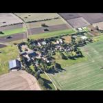 Aerial view of a rural village surrounded by green fields and agricultural land.