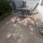 Terrasse mit Gartentisch, vier Stühlen und Sonnenschutz