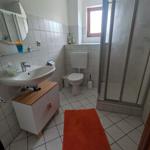 Badezimmer mit Dusche, Toilette und Waschbecken auf Holzunterschrank